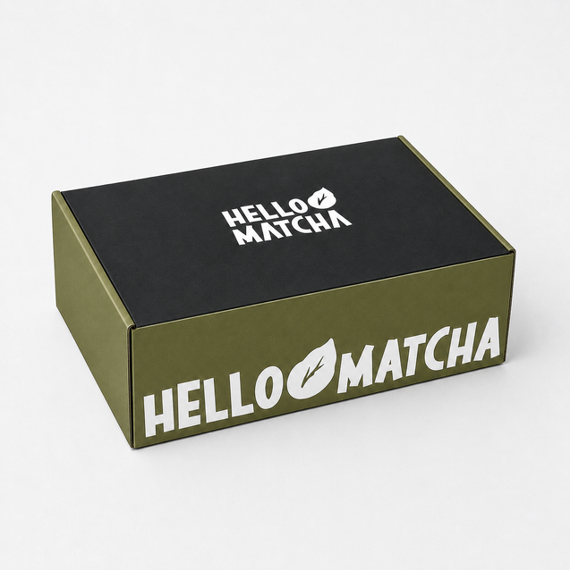 A rectangular Hello Matcha product box shown at an angle on a light gray background. The box has an olive green side and a black top lid, both printed with the white Hello Matcha logo.