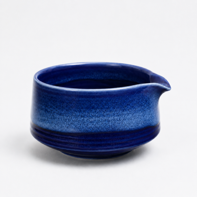 A small ceramic pitcher with a wide pouring spout, featuring a glossy cobalt blue to dark navy gradient glaze on a clean white background.