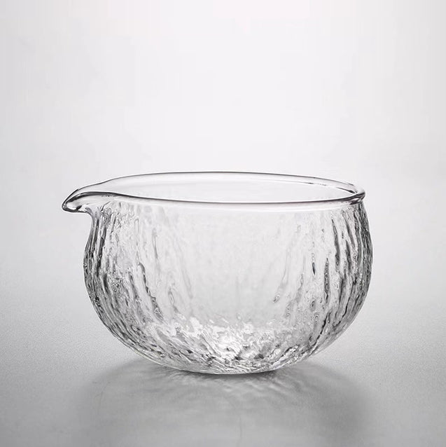 Clear glass bowl with ribbed texture on a light gray background